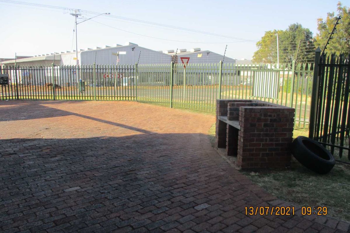 Outdoor area featuring brick paving and a built-in brick braai, enclosed by steel perimeter fencing with electric security wires.