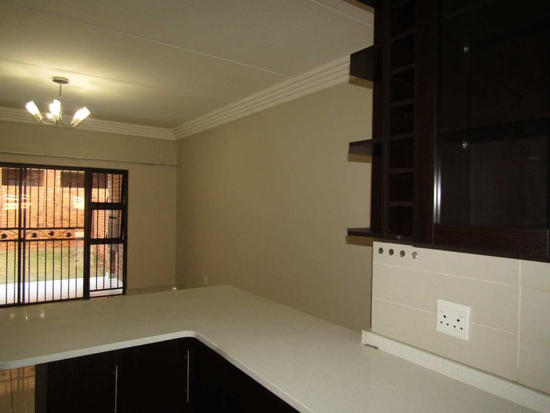 An open-plan living area featuring dark built-in cabinetry, stone countertops, and a security gate leading to an outdoor space.