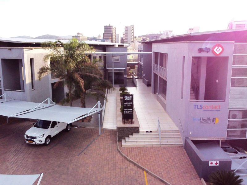 Aerial view of a modern office complex featuring paved parking areas, shade cloth carports, and a central pedestrian walkway between building blocks.