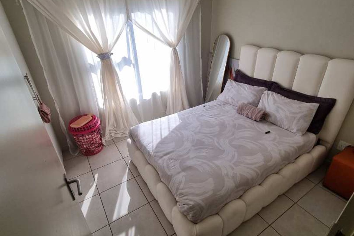 A bedroom featuring tiled flooring and a window with curtain tracks, providing natural light and a functional layout for a comfortable sleeping space.