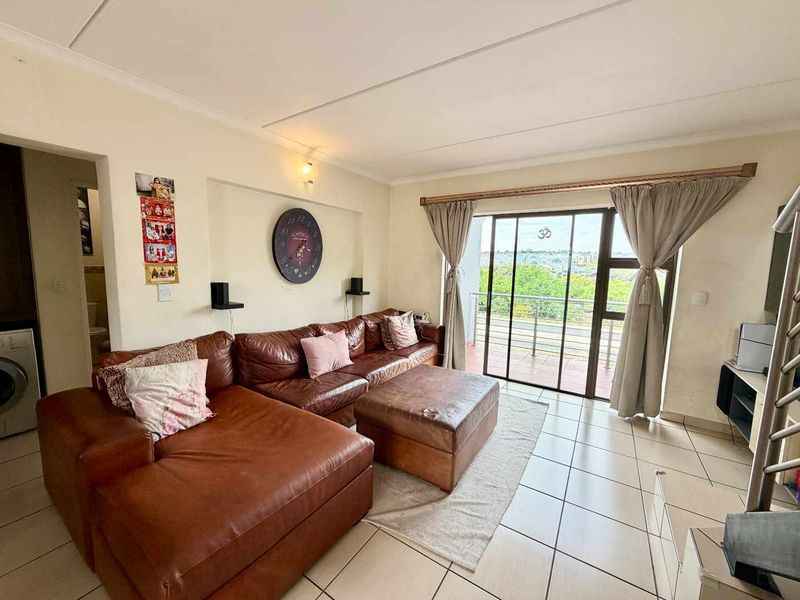 A bright living room featuring tiled flooring and a large sliding glass door that provides access to an outdoor balcony area.