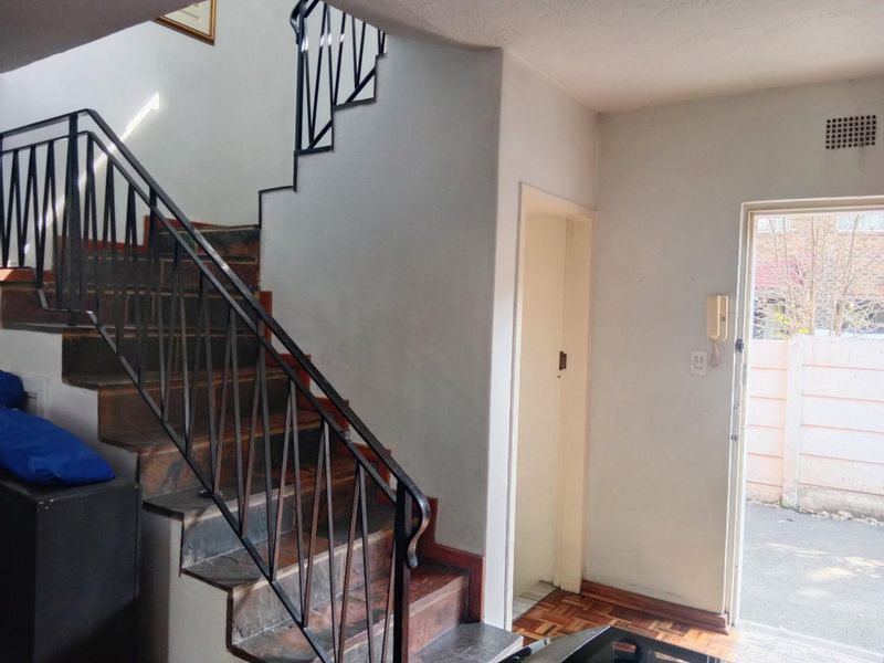 Entrance area featuring a staircase with wrought iron balustrade, parquet flooring, and an intercom system, providing direct access to the exterior.