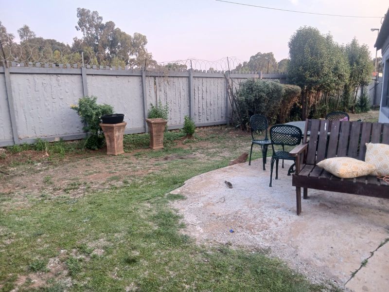 A rear garden area featuring a concrete patio slab, enclosed by a precast concrete wall topped with security razor wire.