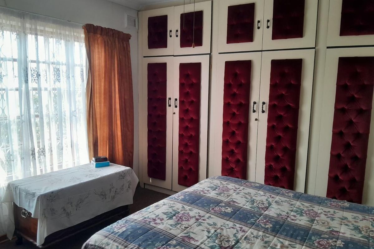 A bedroom featuring extensive built-in cupboards with decorative velvet paneling and a ceiling fan, offering ample storage space.