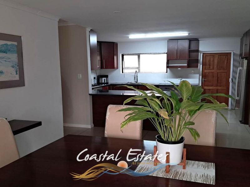 Open plan living and dining area featuring a functional kitchen with dark wood cabinetry and tiled flooring throughout.