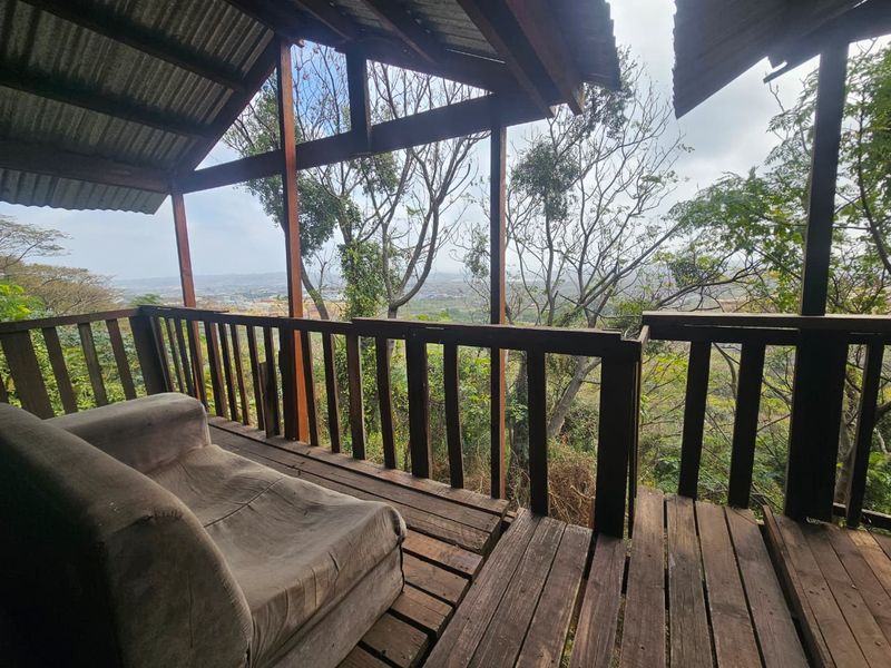 An elevated timber balcony featuring a rustic design with exposed rafters and panoramic views, requiring maintenance to the wooden decking and structural elements.