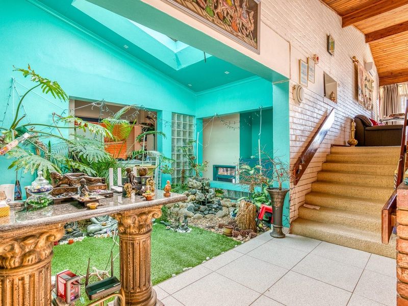 Unique living area featuring a central indoor water feature, skylight, timber-clad ceiling, and a staircase leading to an upper level.