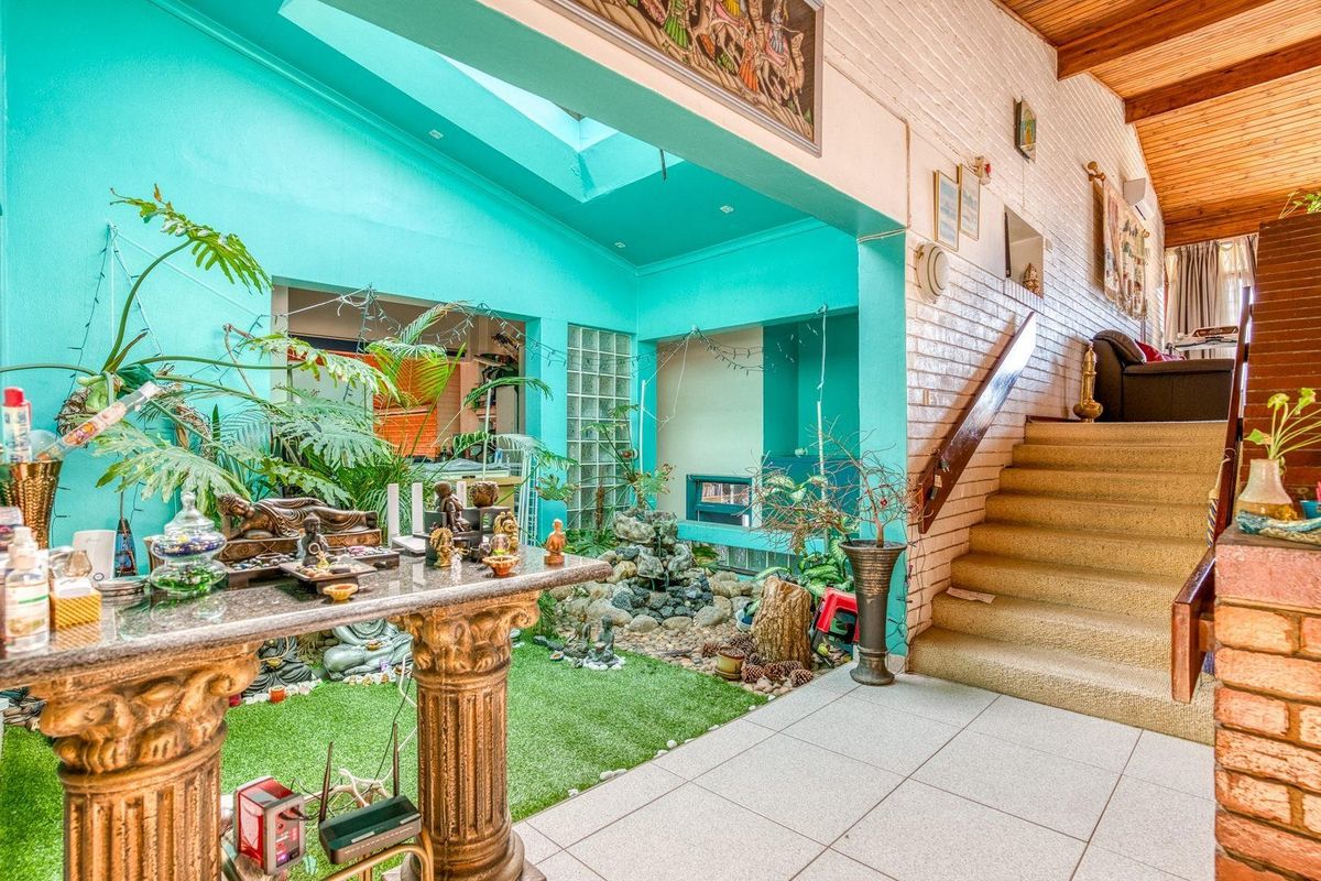 Unique living area featuring a central indoor water feature, skylight, timber-clad ceiling, and a staircase leading to an upper level.