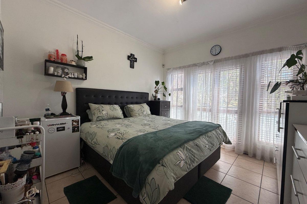 A bedroom featuring tiled flooring, crown molding, and a sliding glass door with integrated blinds and curtains, providing access to the exterior.