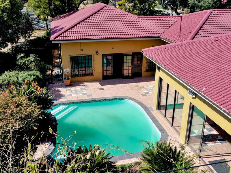 Aerial view of the property featuring a swimming pool, tiled patio area, and terracotta roof tiles.