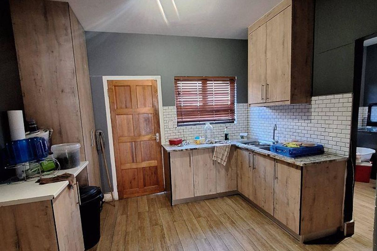 A functional kitchen featuring wood-look cabinetry, subway tile backsplash, stone-effect countertops, and wood-look floor tiles.
