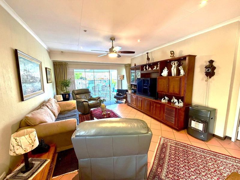 Spacious living room featuring tiled flooring, a ceiling fan, and large sliding glass doors providing access to the outdoor patio area.