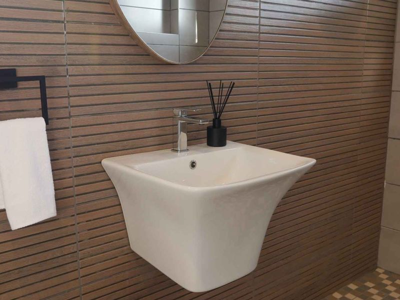 A modern bathroom featuring a sleek wall-mounted basin with chrome mixer tap and contemporary horizontal wood-look wall tiling.