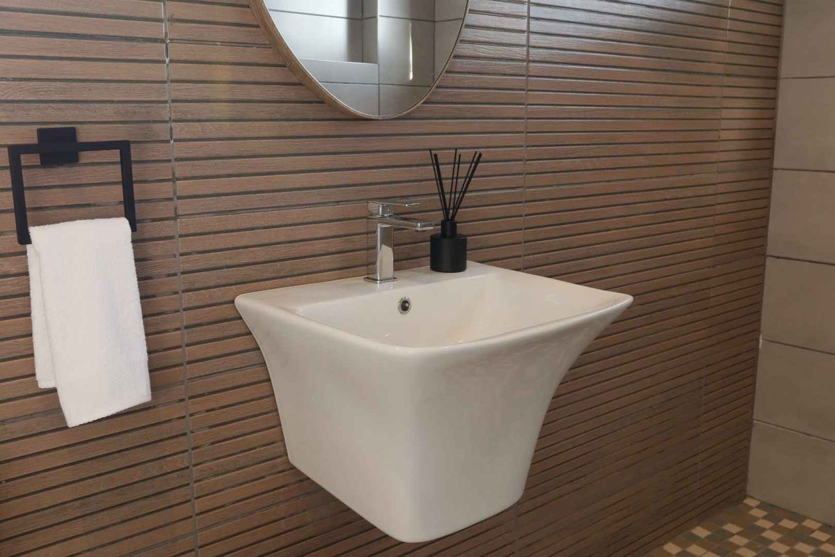 A modern bathroom featuring a sleek wall-mounted basin with chrome mixer tap and contemporary horizontal wood-look wall tiling.