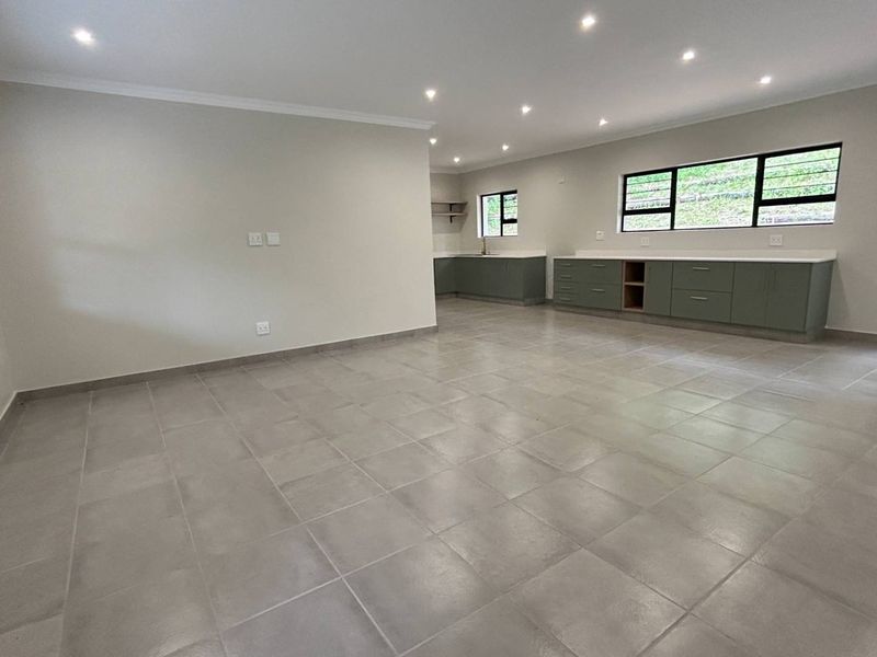 Spacious open-plan living and kitchen area featuring modern tiled floors, recessed lighting, and sleek built-in cabinetry with stone countertops.
