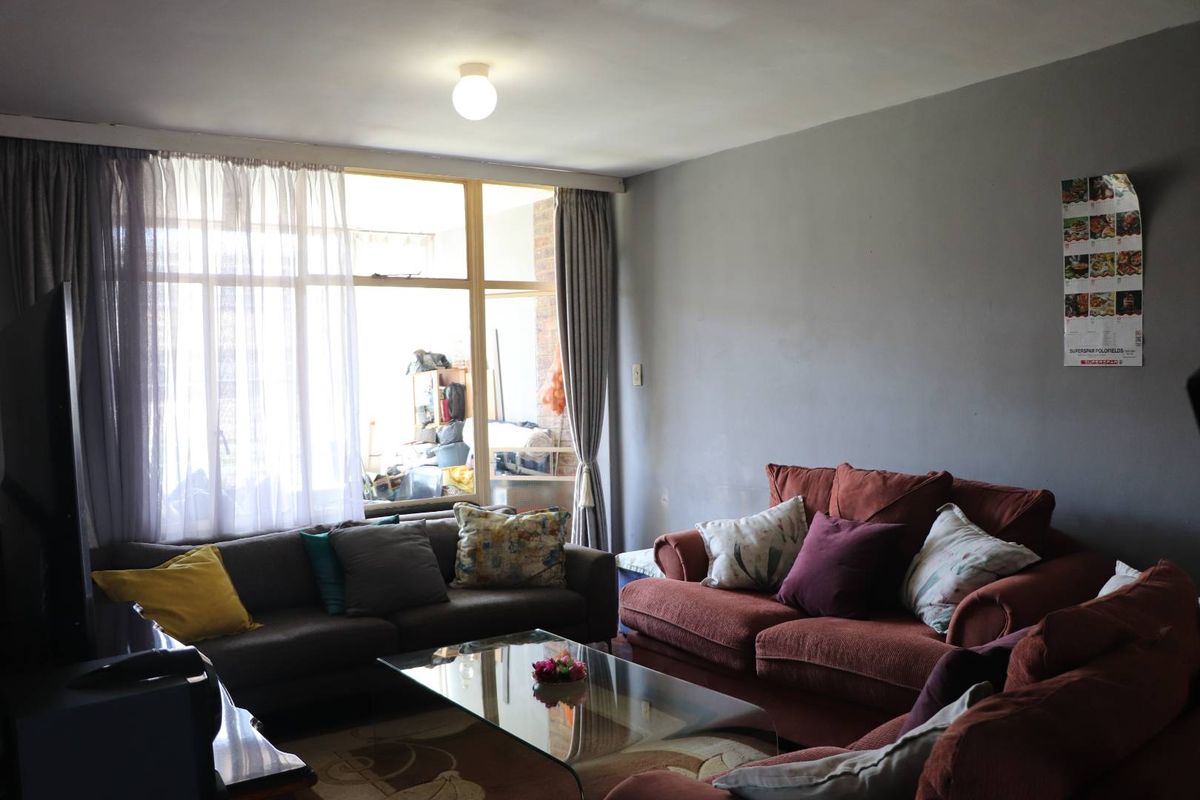 A living room featuring large windows that provide natural light and access to an adjacent balcony area.