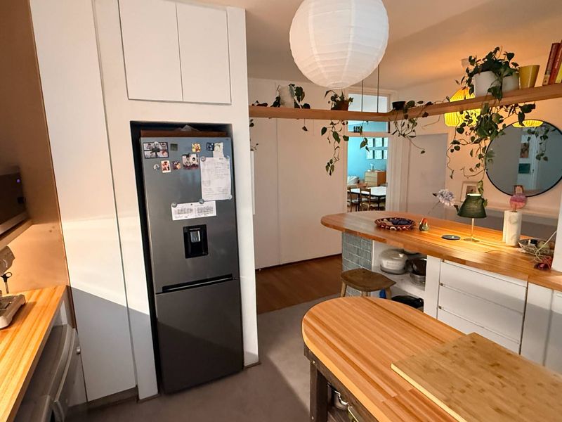 A functional kitchen featuring custom wooden countertops, integrated cabinetry, and a breakfast bar, creating a warm and practical cooking and dining space.