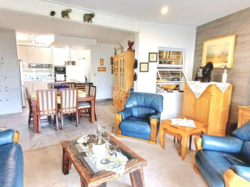Spacious open-plan living and dining area featuring tiled floors, built-in kitchen cabinetry, and large windows allowing for natural light.