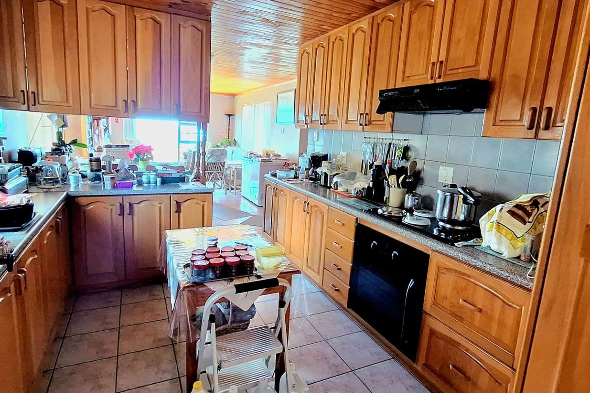A functional kitchen featuring timber cabinetry, tiled flooring, a built-in oven, and a cooktop with an extractor fan.