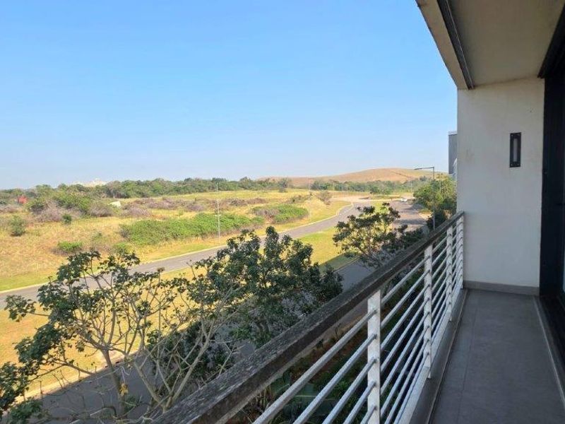 A balcony featuring a metal balustrade and tiled flooring, offering an open view of the surrounding landscape and road.