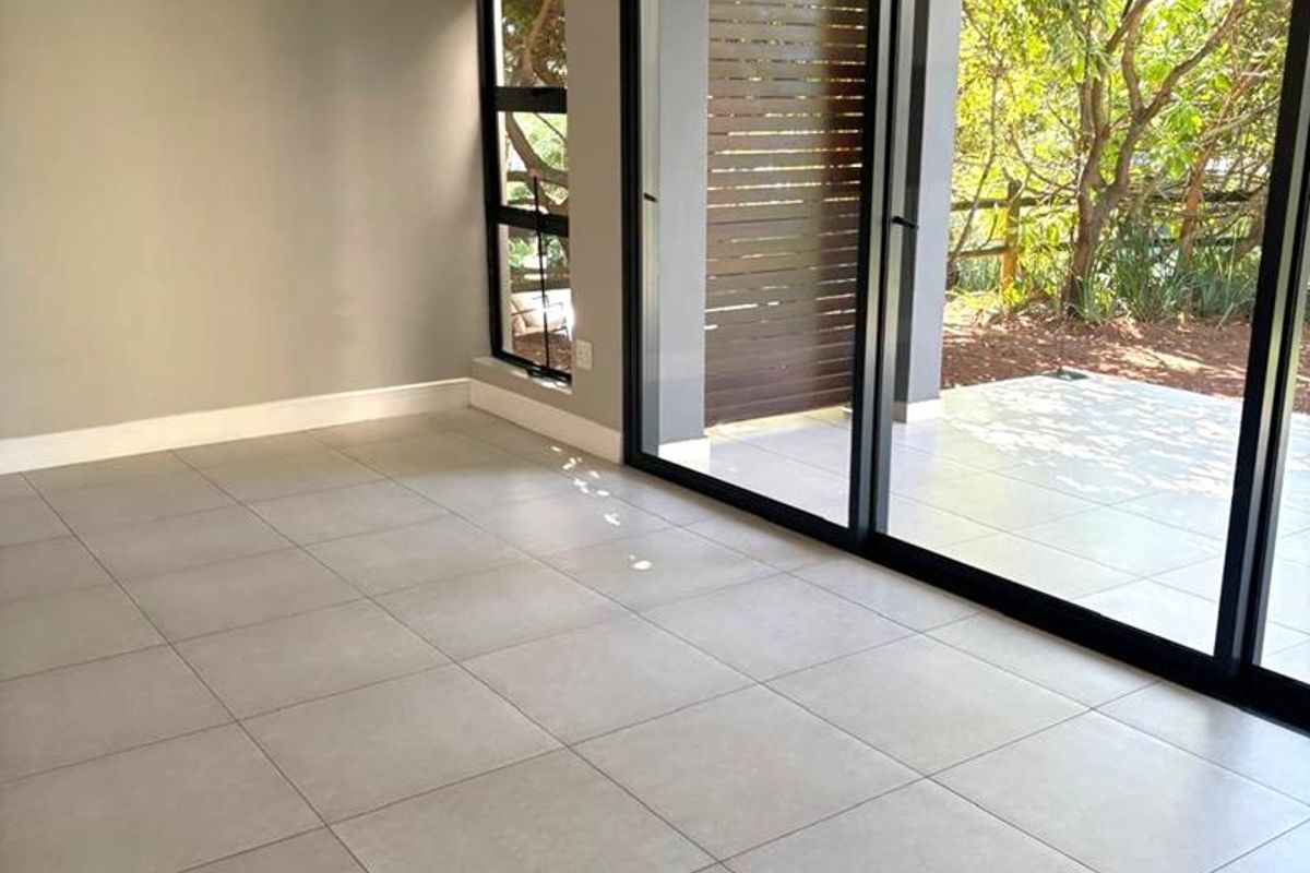 Bright and modern living area featuring large format floor tiles and expansive sliding glass doors that open onto a private patio.