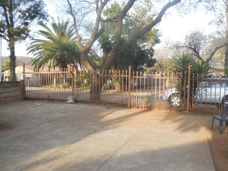 Front exterior view featuring a concrete driveway and a metal spike security fence with a sliding gate.