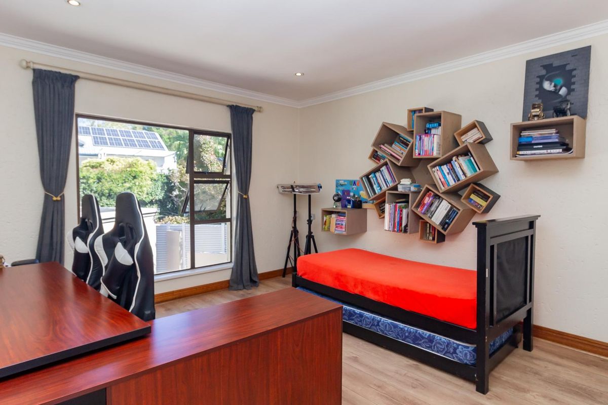A versatile bedroom featuring light wood-look flooring, recessed ceiling lighting, and a large window providing natural light.