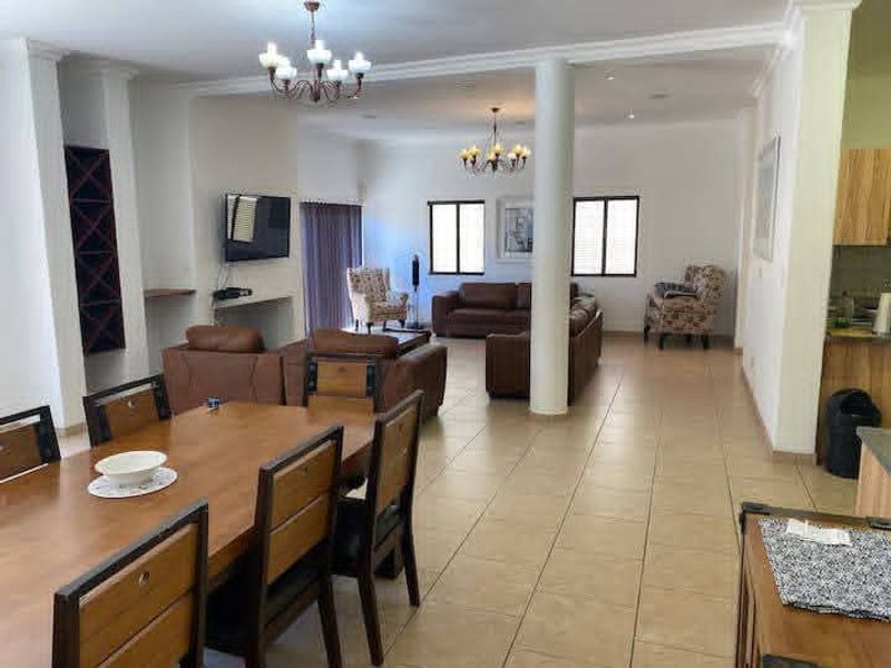 Spacious open-plan living and dining area featuring tiled flooring, structural columns, and integrated wine storage, offering a versatile layout for family living.