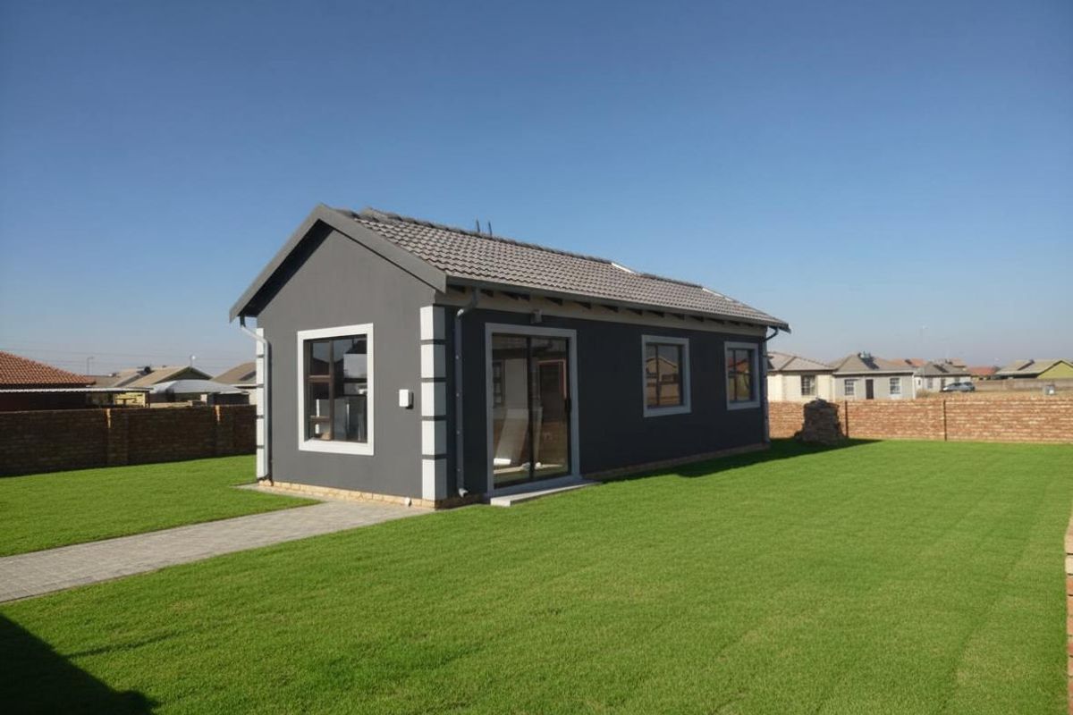 A modern, well-maintained detached dwelling featuring a dark grey exterior finish, tiled roof, and paved walkway set within a neat, landscaped garden.