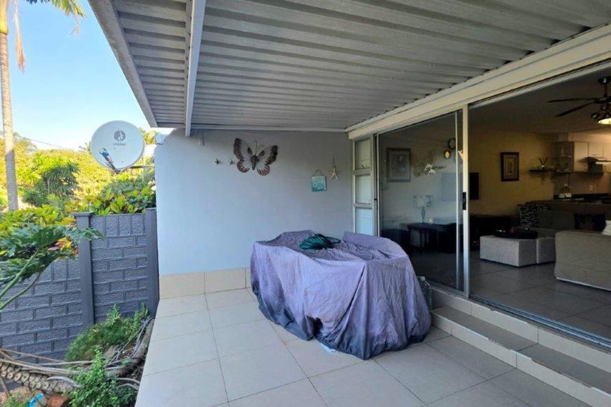 A covered patio area featuring tiled flooring and sliding glass doors that provide access to the interior living space.