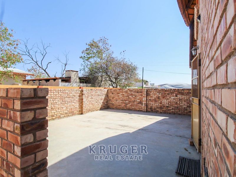 A private, paved outdoor patio area enclosed by face-brick boundary walls, offering a functional space for outdoor living.
