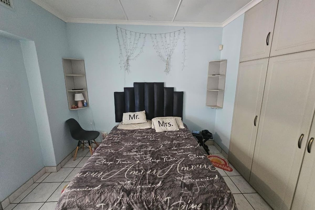 A bedroom featuring built-in cupboards, wall-mounted shelving units, and tiled flooring.