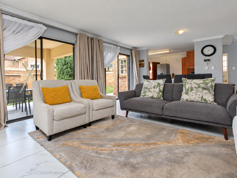 Spacious open-plan living area featuring large sliding glass doors leading to a patio, polished tiled flooring, and a neutral color palette.