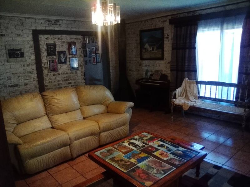 A living room featuring exposed brick walls, ceramic tile flooring, and a sliding glass door providing natural light.