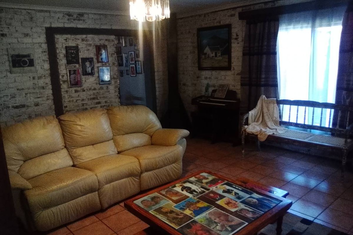 A living room featuring exposed brick walls, ceramic tile flooring, and a sliding glass door providing natural light.