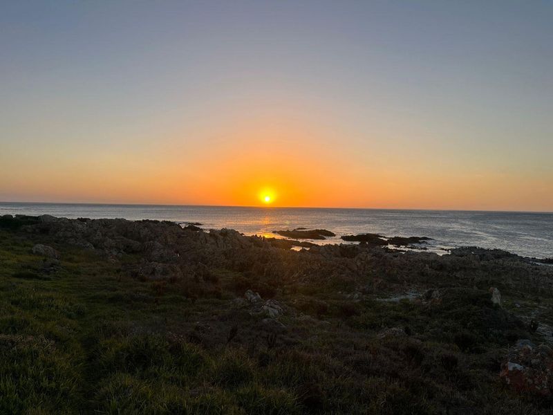 A scenic sunset view over the rocky coastline and ocean, highlighting the property's natural surroundings and coastal location.