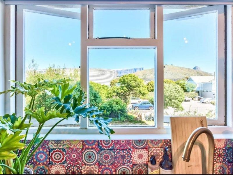 A kitchen window view featuring a patterned tile backsplash, a modern faucet, and a scenic outlook towards the mountain.