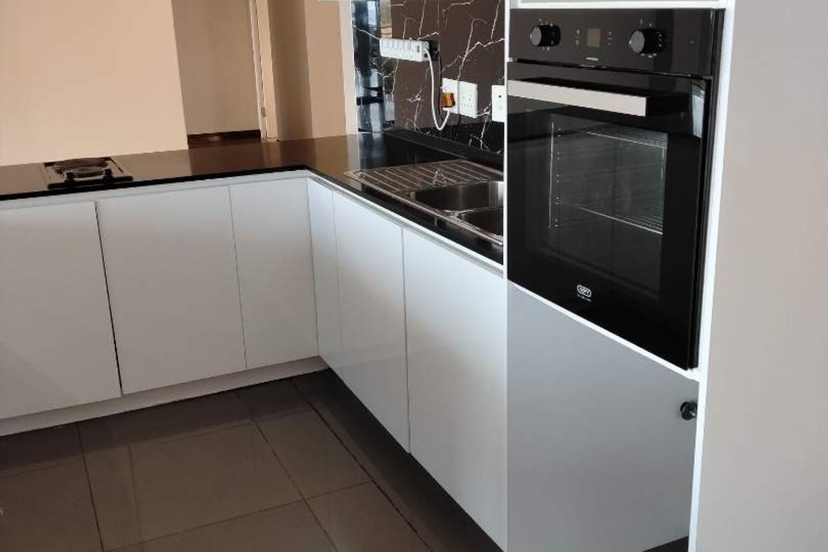 Modern kitchen featuring glossy white cabinetry, black stone countertops, marble-effect splashback, and a built-in oven with sleek ceramic floor tiling.