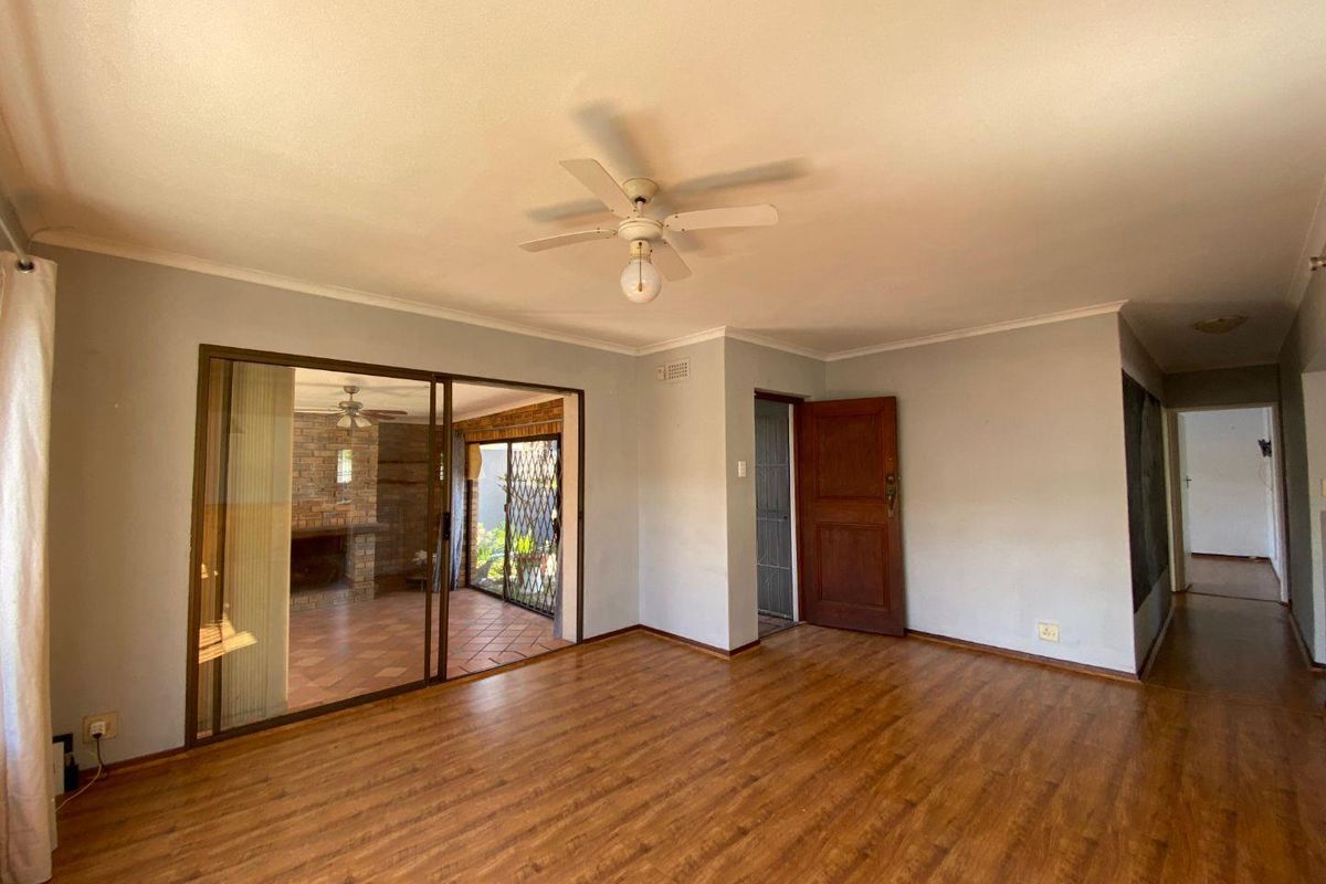 Spacious living room featuring laminate flooring, a ceiling fan, and sliding glass doors providing access to an outdoor patio area.