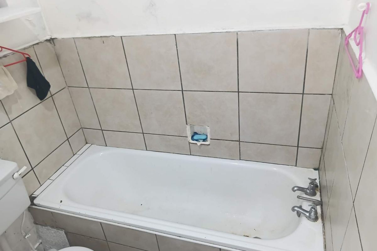 A functional bathroom featuring a standard bathtub with wall tiling and basic fixtures, currently requiring maintenance and cosmetic updates.
