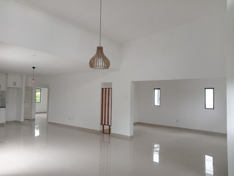 Spacious open-plan living area featuring polished porcelain tiles, neutral white walls, and modern pendant lighting, offering a bright and versatile blank canvas.