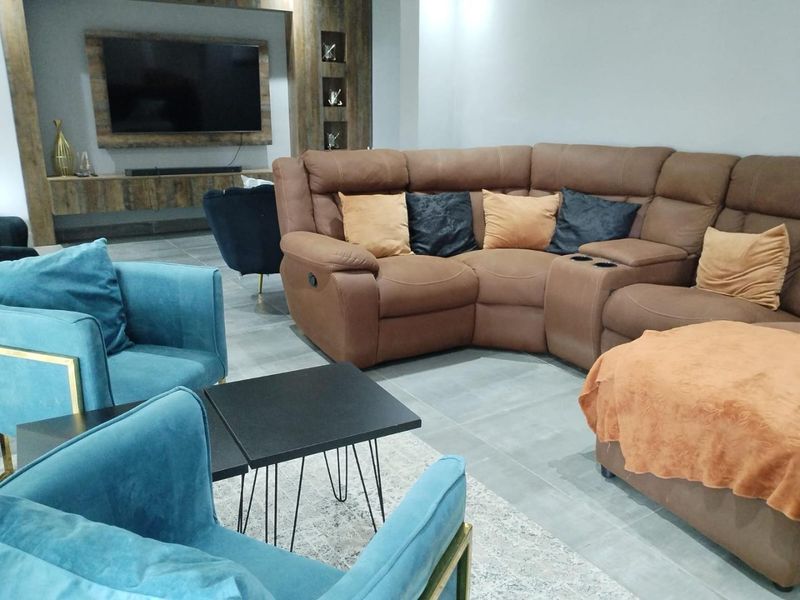 Spacious living room featuring a modern built-in media wall with recessed shelving and large format floor tiles.