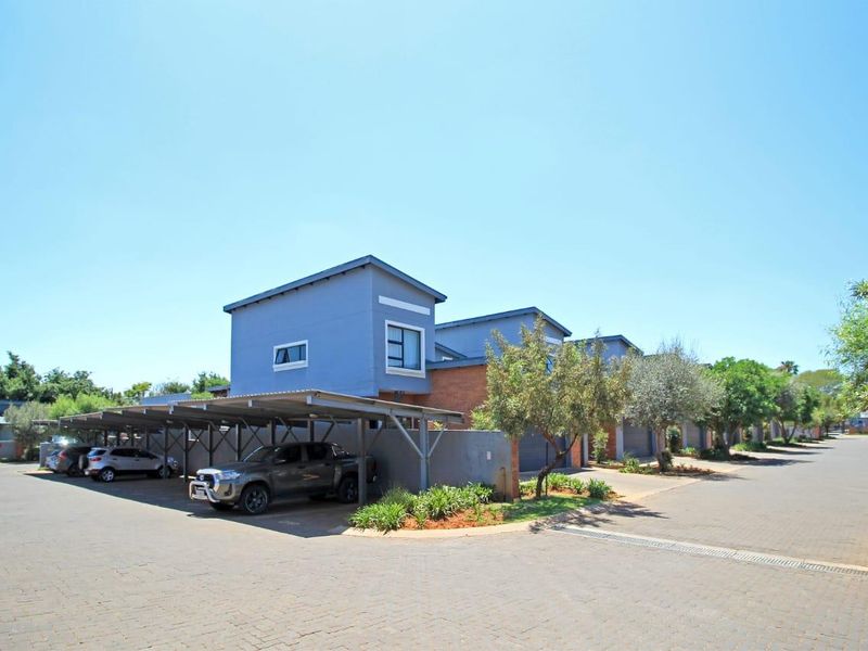 Exterior view of the apartment complex featuring covered parking bays and paved driveway access.