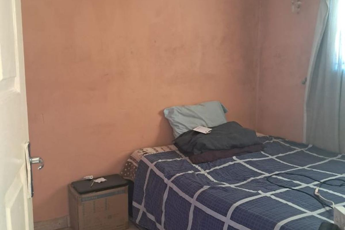 A compact bedroom featuring tiled flooring and a textured ceiling, currently requiring cosmetic updates to the wall finishes and ceiling maintenance.