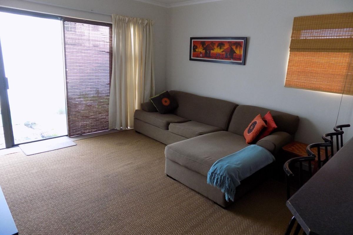A living room area featuring carpeted flooring and a large sliding glass door providing access to the exterior.