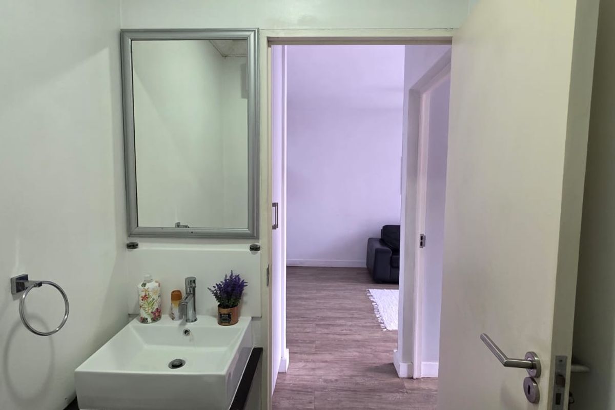 A functional bathroom featuring a modern wall-mounted basin with a chrome mixer tap and a wall-mounted mirror, providing a clean and practical space.