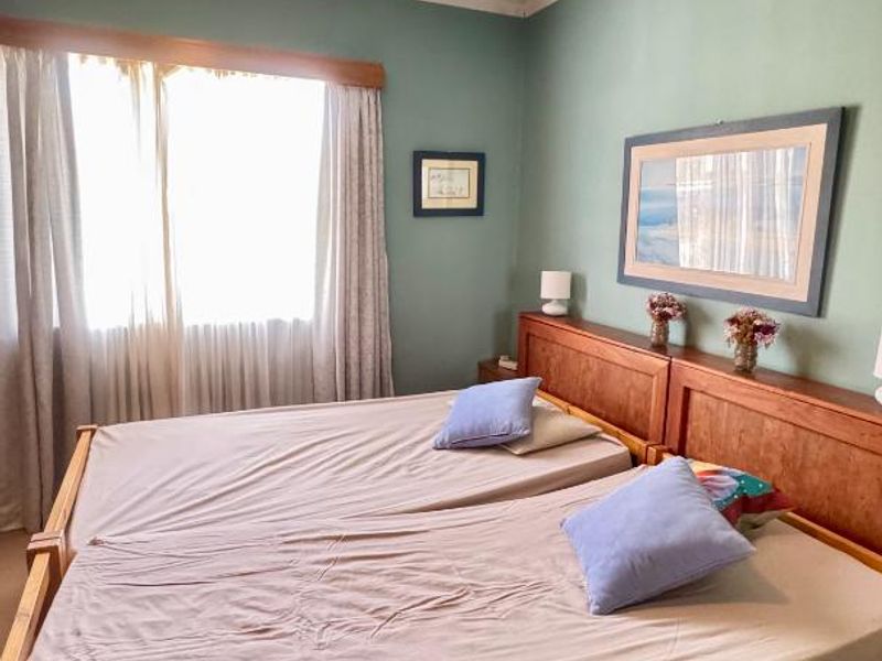A bedroom featuring a ceiling fan, crown molding, and a built-in wooden headboard, offering a functional space with potential for modern updates.