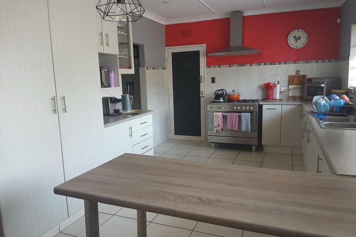 A functional kitchen featuring white cabinetry, tiled flooring, a stainless steel gas stove with extractor fan, and a breakfast bar island.