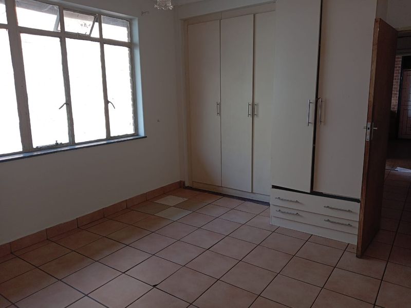 An empty bedroom featuring tiled flooring and built-in cupboards, offering a blank canvas for personalization and renovation.