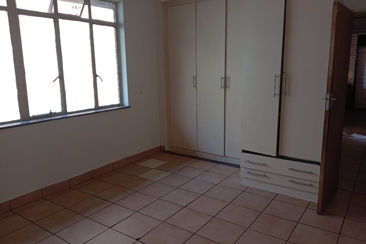 An empty bedroom featuring tiled flooring and built-in cupboards, offering a blank canvas for personalization and renovation.